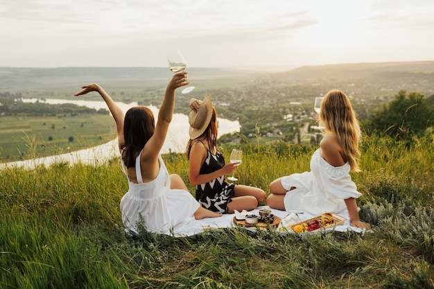 Des femmes heureuses trinquent avec du vin blanc sur la montagne avec rivière