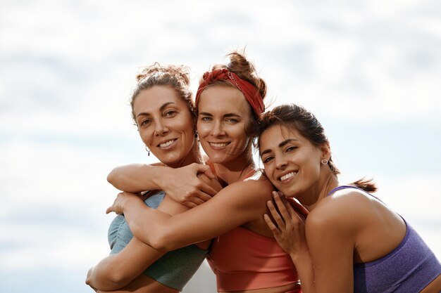 Femmes heureuses en vêtements de fitness se détendre et s'amuser dans le parc au bord de la rivière Fitness sport amitié et concept de mode de vie sain Groupe de personnes heureuses faisant de l'exercice