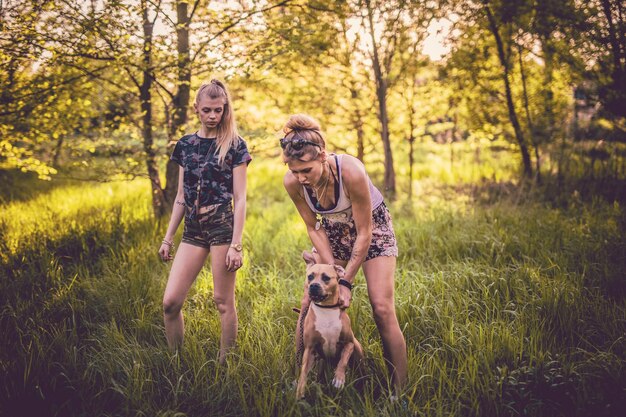 Photo des femmes jouant avec un chien sur un champ herbeux.