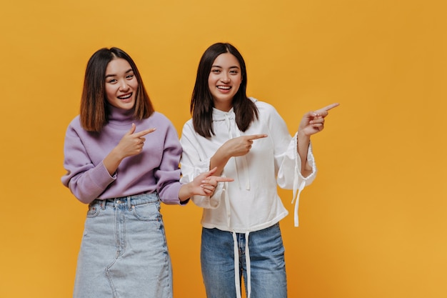 Des femmes joyeuses et joyeuses pointent à la place du texte sur le mur orange