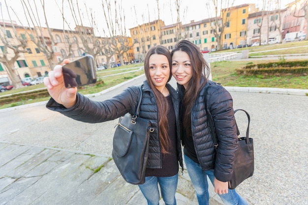 Femmes jumelles prenant un selfie dans la ville.