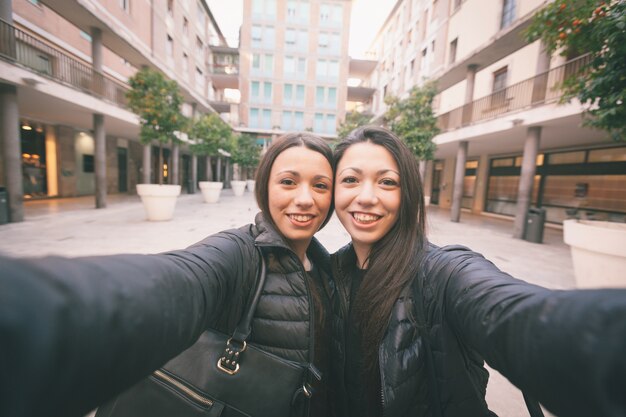 Femmes jumelles prenant un selfie dans la ville.