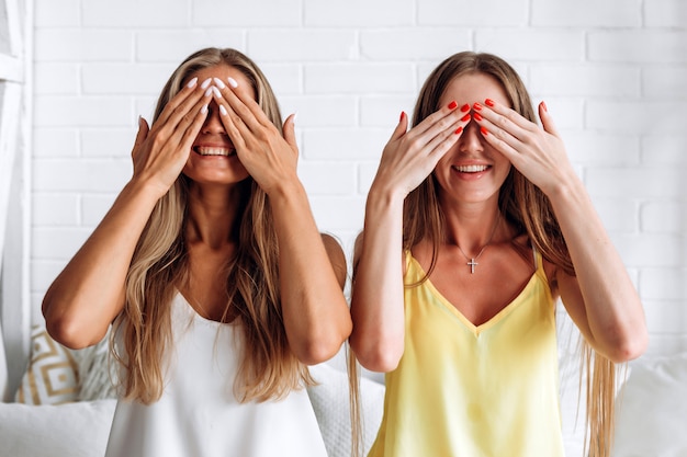 Les femmes sur le lit couvrent les yeux avec les mains, un large sourire attend une surprise