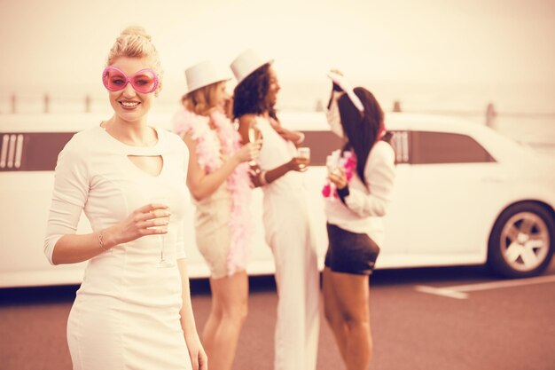 Femmes avec des lunettes de soleil tenant du champagne en se tenant debout sur le parking