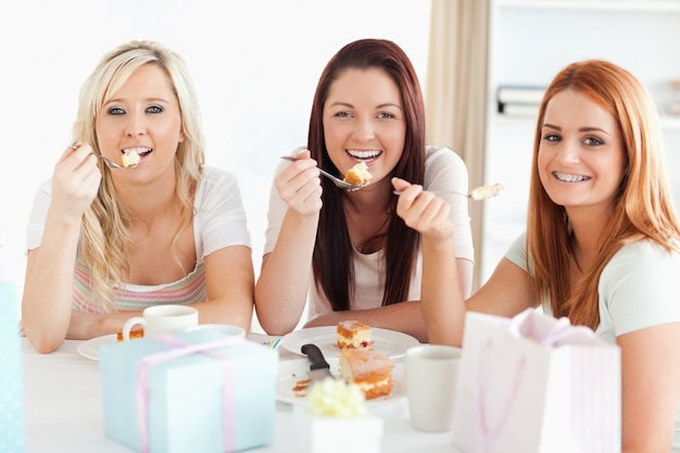 Femmes magnifiques assis à une table en train de manger un gâteau