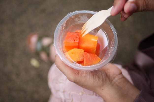 Femmes mangeant de la papaye et du raisin dans un récipient en plastique à emporter