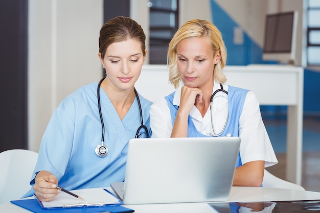 Femmes médecins utilisant un ordinateur portable assis au bureau