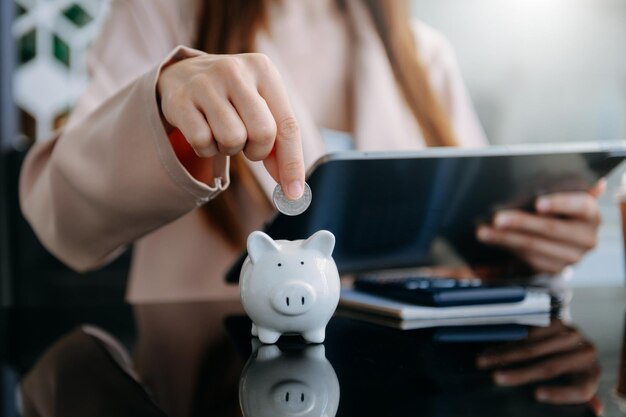 Les femmes mettent des pièces dans une tirelire pour une entreprise qui se développe à des fins lucratives et économise de l'argent pour la planification future