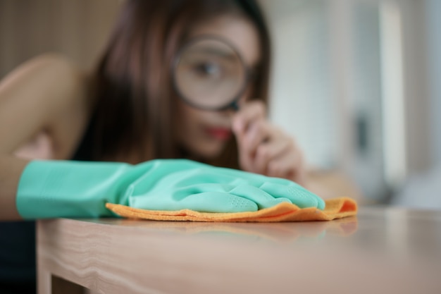 Femmes Nettoyage à la main de la table avec une loupe pour la protection contre les virus.