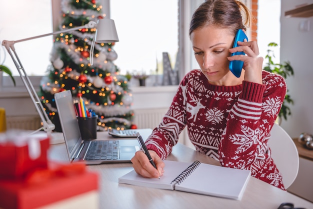 Femmes parlant sur un téléphone intelligent et écrivant des notes