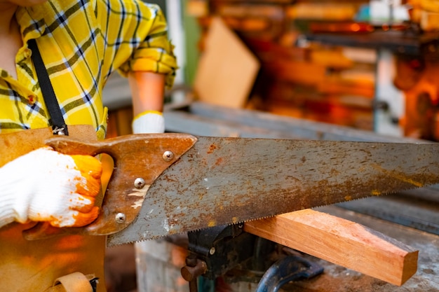 Les femmes part debout scier une planche de bois sur fond bavure