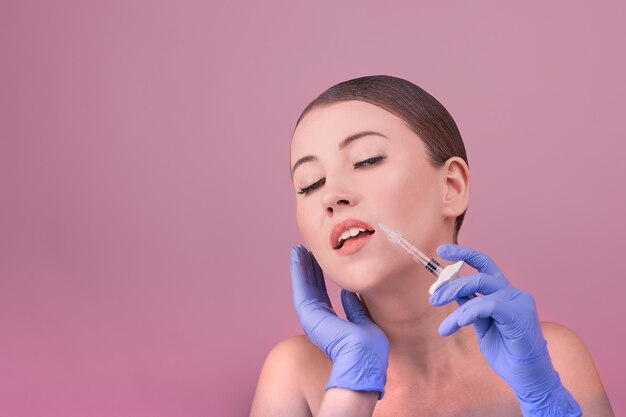 Les femmes à la peau parfaite posent une seringue à la main. Image conceptuelle des victimes de chirurgie plastique