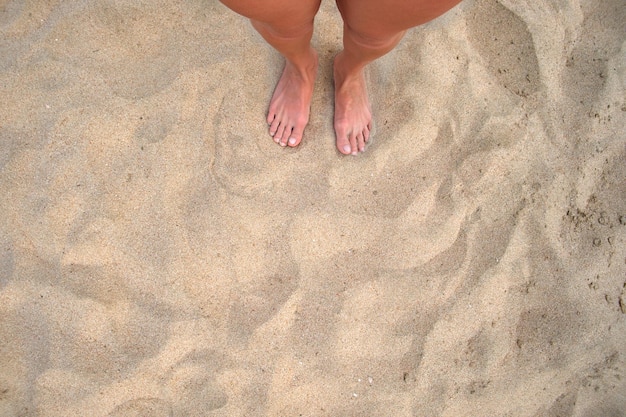 Des femmes pieds nus sur le sable de la plage.