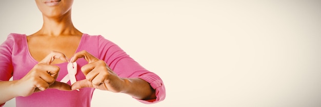 Femmes portant une chemise rose faisant un cœur avec leurs doigts autour d'un ruban rose