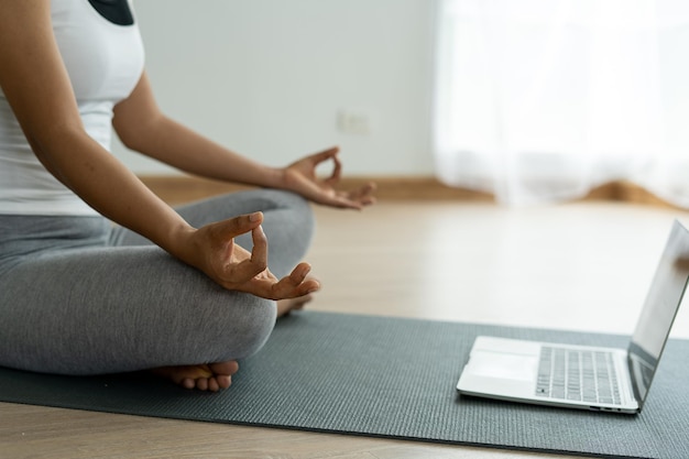 Les femmes portant des vêtements d'exercice yoga posture assise calme se détendre à la maison Les femmes apprennent le yoga en ligne via une tablette Idées de mode de vie sain