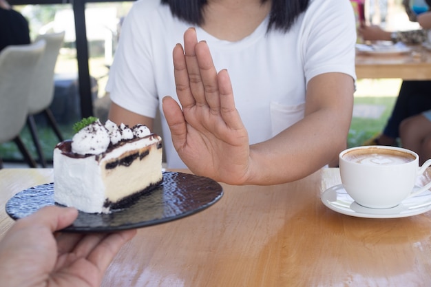 Les femmes poussaient l'assiette à gâteau avec les gens. Ne mangez pas de desserts pour perdre du poids.