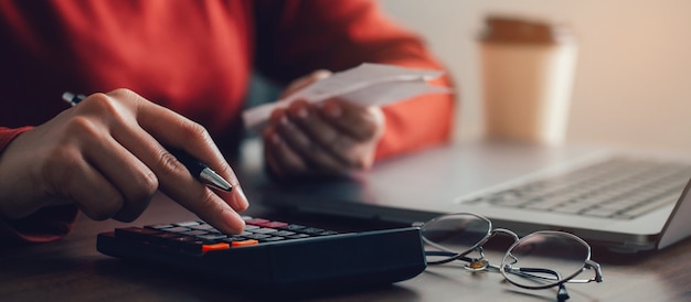 les femmes qui utilisent des calculatrices calculent les factures domestiques à la maison les jeunes femmes font de la paperasse