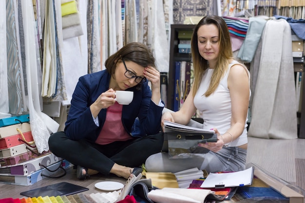 Les femmes regardent des échantillons de tissus pour rideaux, meubles