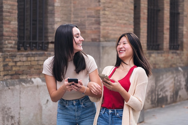 Femmes riant amusées avec des téléphones portables à la main