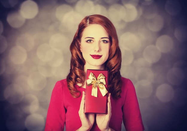 Femmes rousses avec cadeau. Photo avec bokeh en arrière-plan.