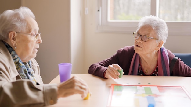 Photo des femmes s'amusent à jouer au jeu de plateau parcheesi dans un geriatric