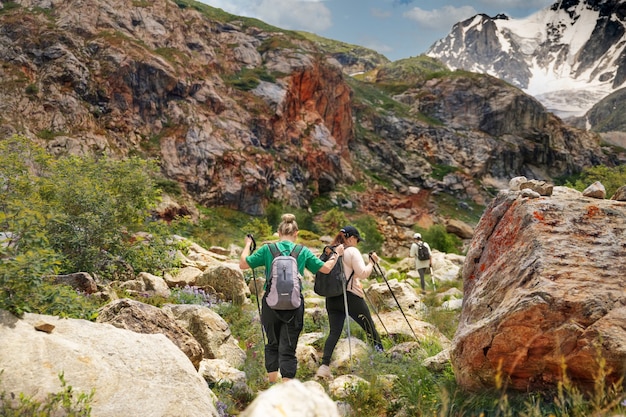 Des femmes avec des sacs à dos et des bâtons scandinaves escaladent les montagnes du Caucase