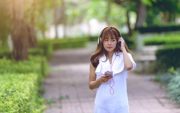 Les femmes se détendent d&#39;écouter de la musique avec des écouteurs sur l&#39;application de téléphone intelligent après pour le coureur