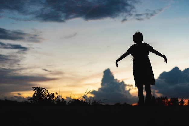 Les femmes silhouettes lèvent joyeusement la main au coucher du soleil.