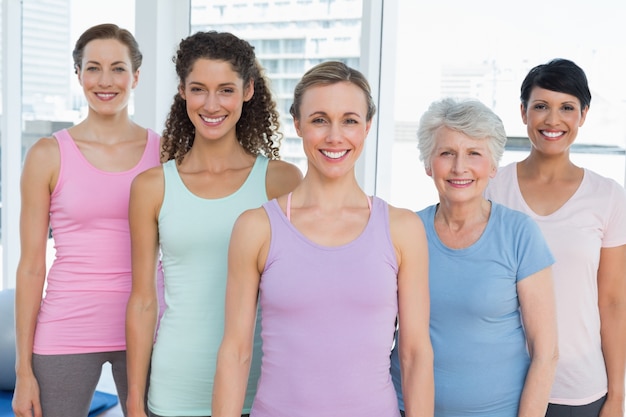 Femmes souriantes debout dans le cours de yoga