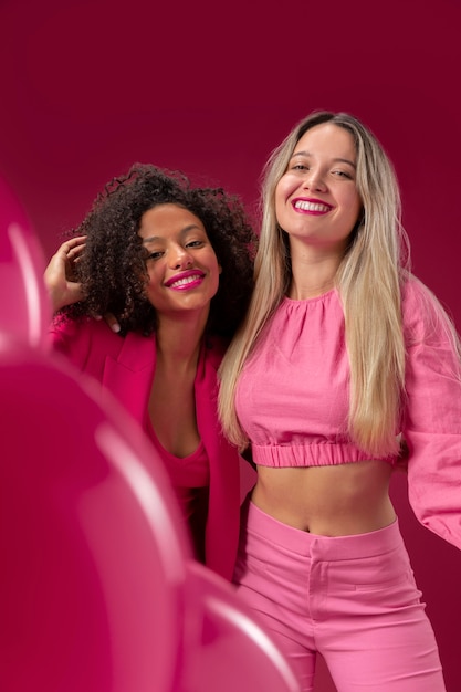 Photo femmes souriantes de plan moyen avec des ballons roses