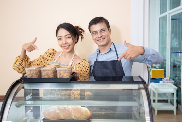 Femmes souriantes tenant des cookies dans un café en tant que propriétaire de petite entreprise.