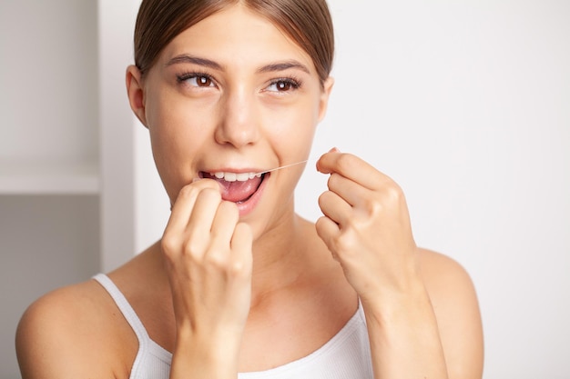 Les femmes souriantes utilisent du fil dentaire blanc dents saines.