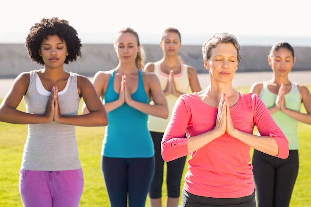 Femmes sportives pacifiques faisant la position de prière dans le cours de yoga