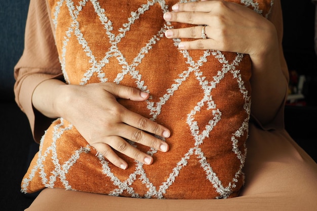 femmes tenant un oreiller de couleur orange tout en étant assises sur un canapé