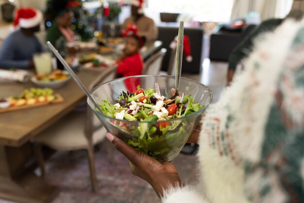 Photo femmes tenant une salade famille afro-américaine passant du temps ensemble et prenant un repas. noël, temps en famille et concept de célébration.