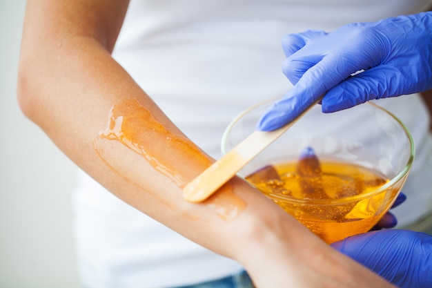 Les femmes tiennent un bol de paraffine orange. Femme dans un salon de beauté