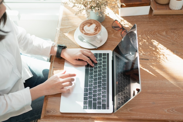 Femmes travaillant sur la table avec un ordinateur portable et prenant des idées au café