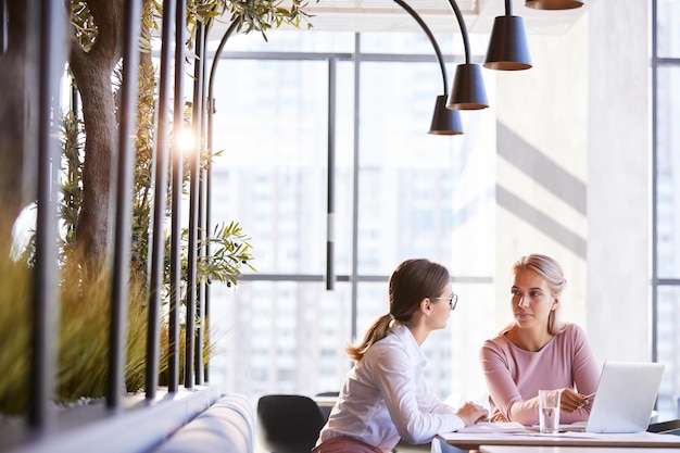 Femmes utilisant un ordinateur portable ensemble au café