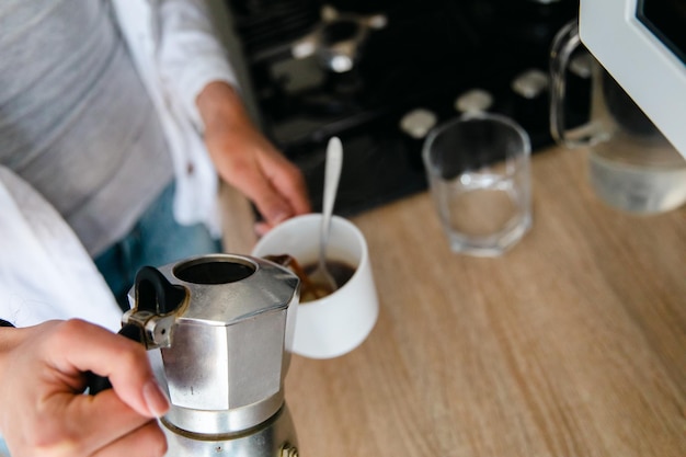 Femmes versant du café expresso dans une tasse à partir d'un pot de moka