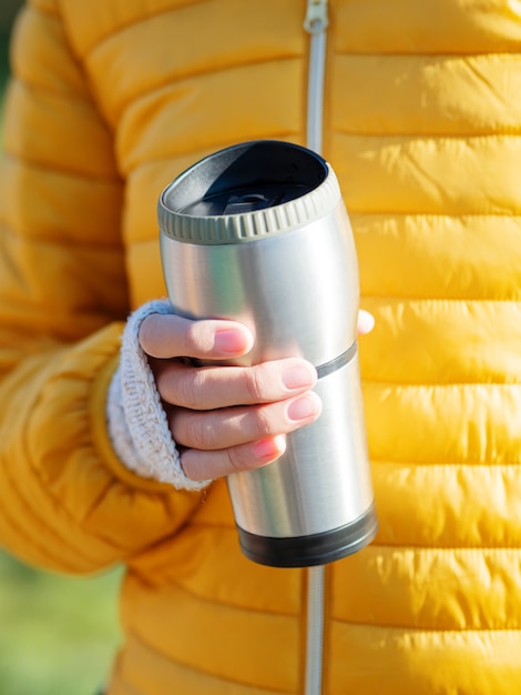 Photo les femmes en veste jaune vif tient une tasse de thermos