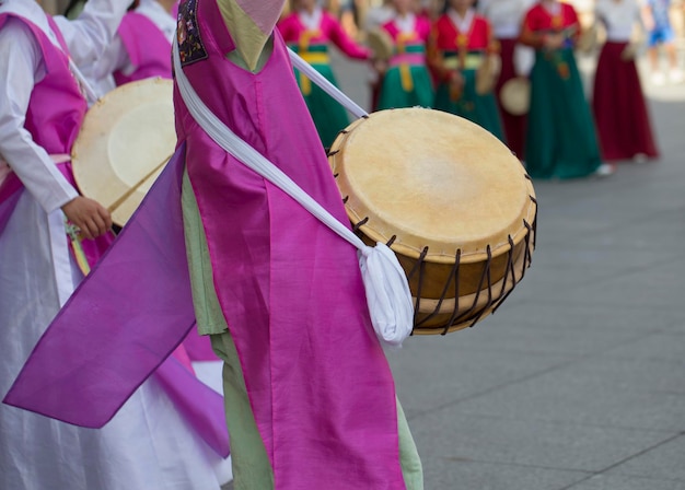 Des femmes en vêtements traditionnels avec des tambours dansant sur un trottoir de la ville