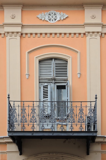 Fenêtre et balcon avec clôture en fer à l'ancienne sur le mur orange avec ornements