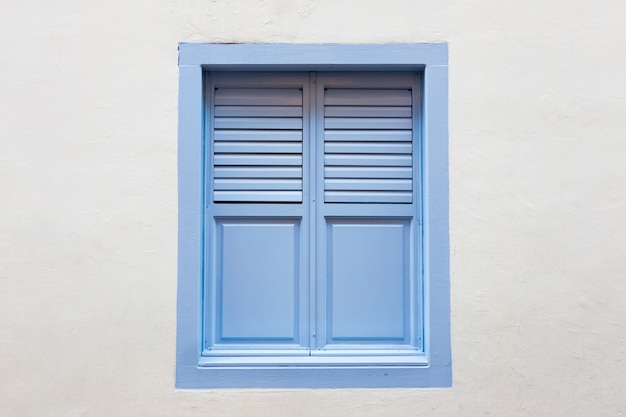 Fenêtre en bois bleue est un style vintage classique sur fond de mur de ciment blanc.