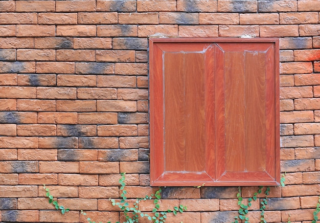Fenêtre en bois sur fond de mur de briques rouges.