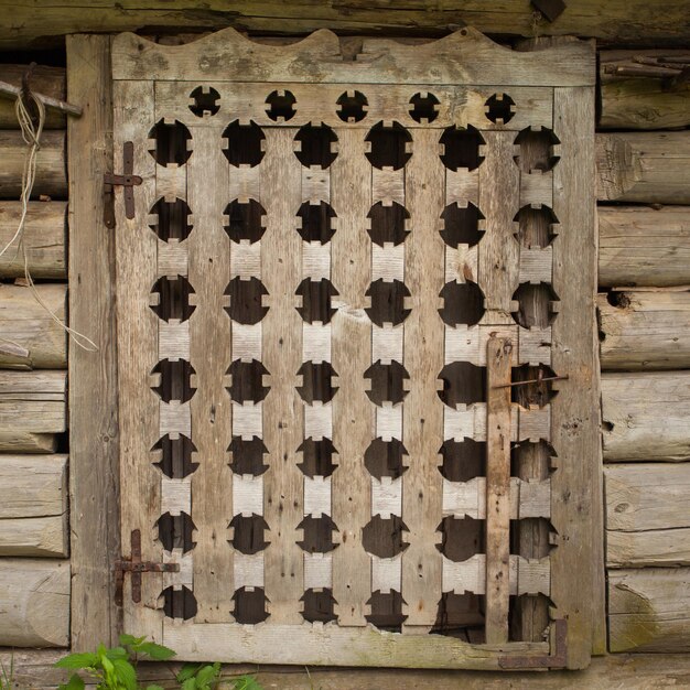 Fenêtre en bois avec texture rugueuse entourée de planches dans le vieux bâtiment