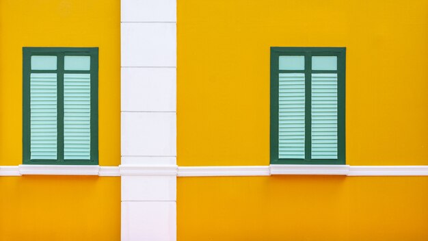 Fenêtre en bois vert et bleu classique du bâtiment en béton jaune.