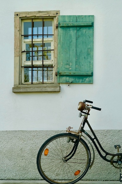 Fenêtre en bois vert avec un vieux vélo ci-dessous