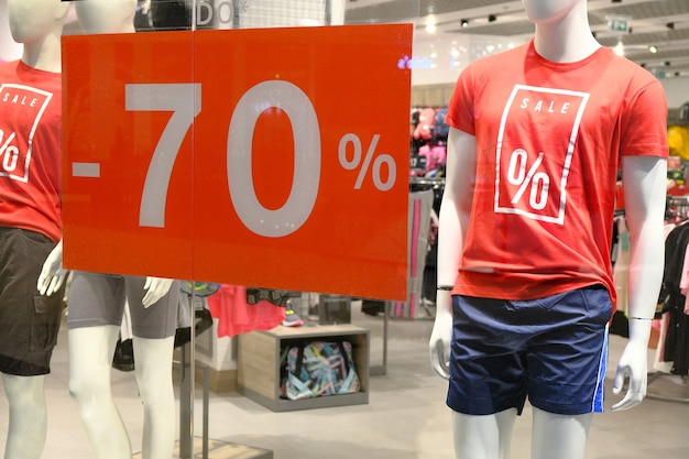 Fenêtre de la boutique avec mannequin en t-shirt avec signe publicité vente pour vêtements de sport