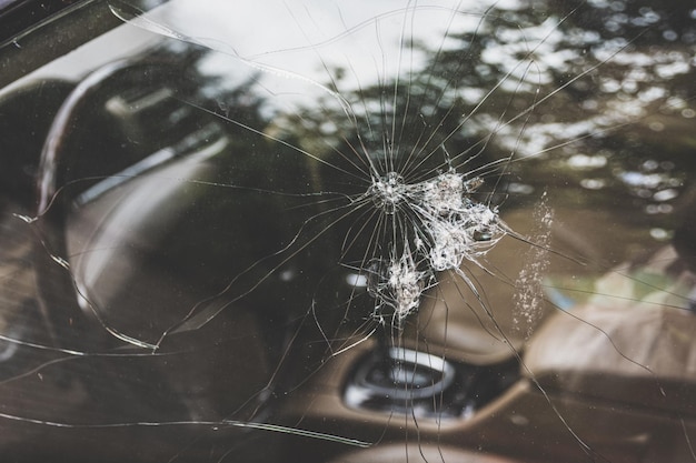 La fenêtre fissurée de la voiture avec des motifs et des trous