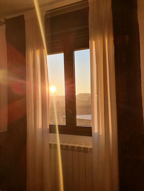 une fenêtre de fond avec des rideaux à travers lesquels le soleil levant entre